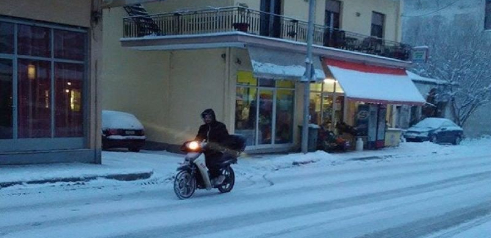 Διανομείς παίρνουν το μηχανάκι στα χέρια για να παραδώσουν την παραγγελία μέσα στο χιόνι